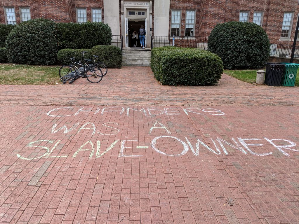 A picture of the brick path outside of Chambers. The words "Chambers was a slave-owner" is woritten in chalk on the ground.